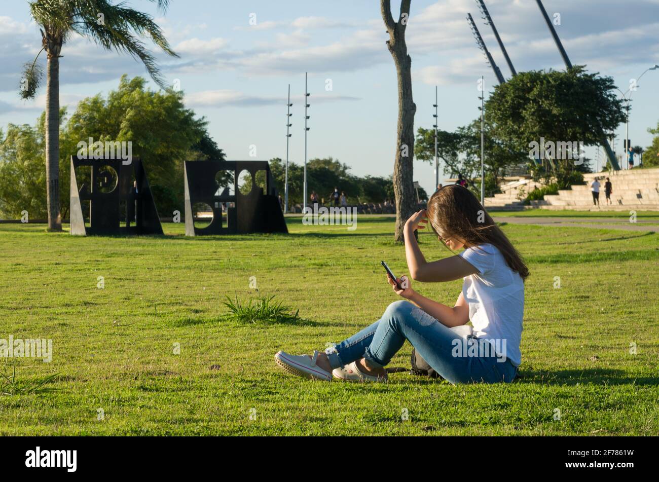 Young Woman Sitting On The Grass Using Smartphone On The New Orla Do Guaiba In Porto Alegre On Beautiful Sunset Day Stock Photo Alamy