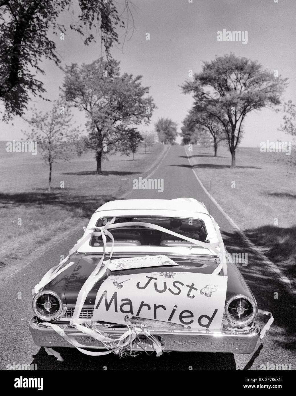 1960s ANONYMOUS NEWLYWED COUPLE IN CONVERTIBLE CAR WITH