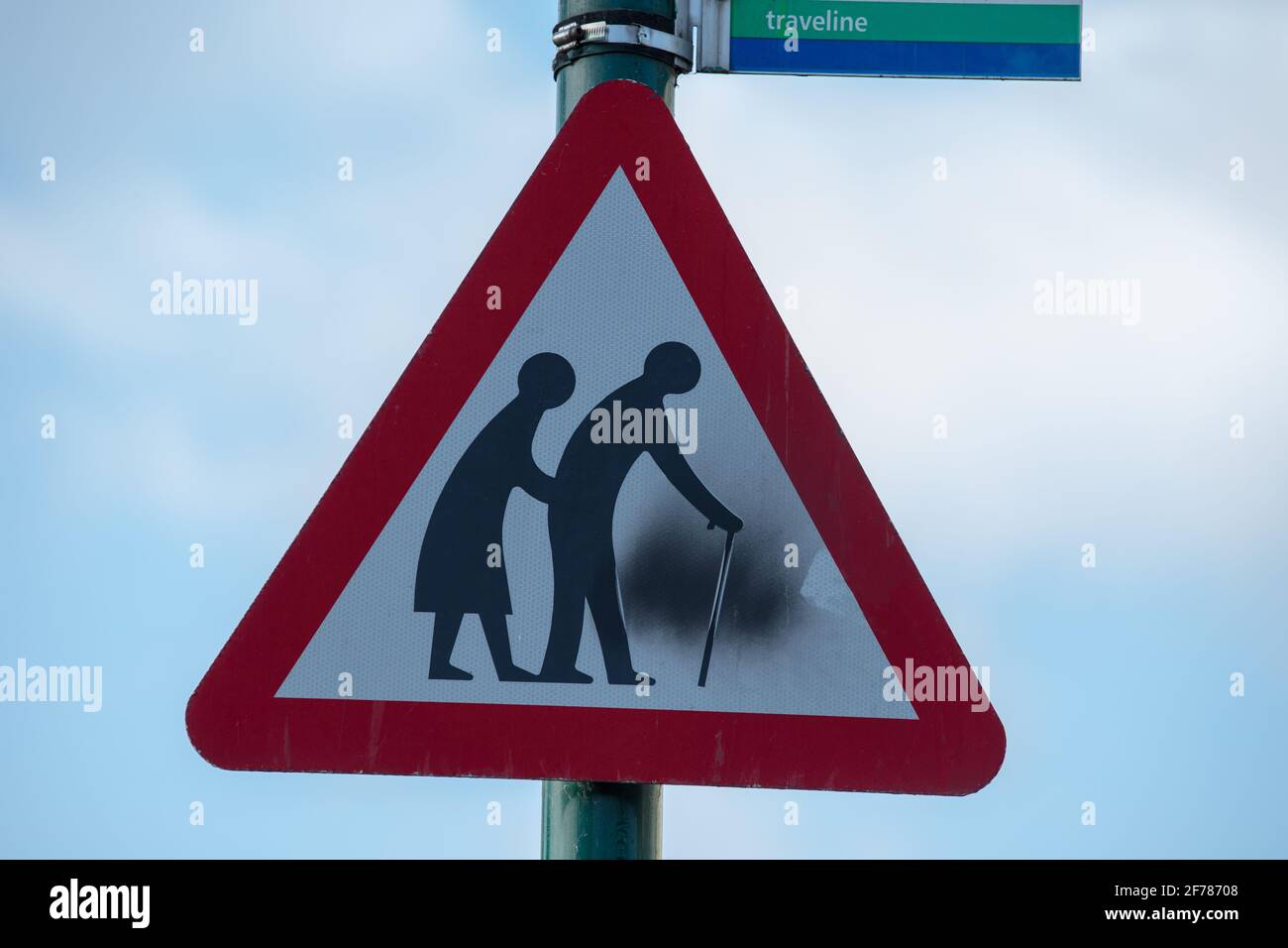 Elderly people crossing triangular warning road sign. Stock Photo