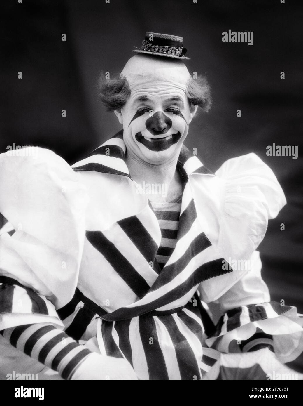 1930s SMILING BIG TOP CIRCUS WHITEFACE CLOWN LOOKING AT CAMERA WEARING TINY HAT STRIPED OVERSIZE COSTUME - c2681 HAR001 HARS COPY SPACE HALF-LENGTH MAKEUP PERSONS INSPIRATION TRADITIONAL CHARACTER MALES ENTERTAINMENT SPIRITUALITY CONFIDENCE B&W SADNESS CLOWNS EYE CONTACT HUMOROUS HAPPINESS WELLNESS CHEERFUL PERFORMER STRENGTH EXCITEMENT OVERSIZE TRADITION MAKE UP COMICAL PRIDE ENTERTAINER OCCUPATIONS SMILES WHITEFACE COMEDY ESTABLISHED JESTER JOYFUL STYLISH TINY MID-ADULT MID-ADULT MAN BIG TOP BLACK AND WHITE FOOL HAR001 OLD FASHIONED Stock Photo