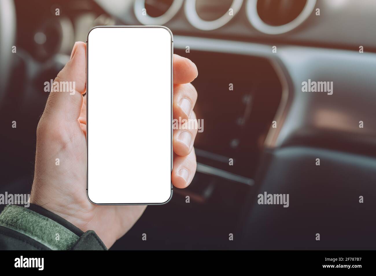 Mobile smart phone device in male hand, mock up with blank white screen. Man sitting in car and holding smartphone. Stock Photo