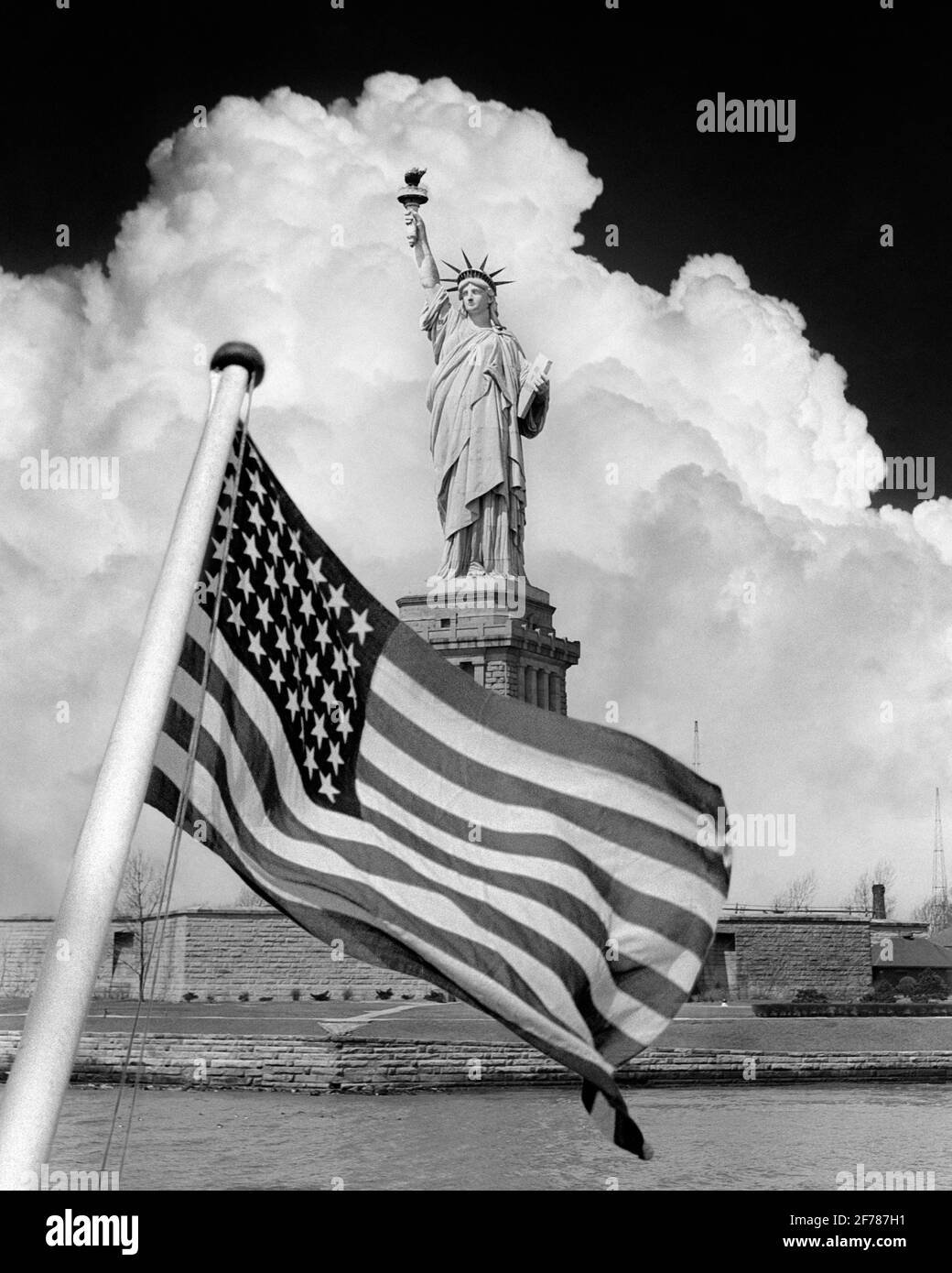 1940s COMPOSITE IMAGE OF STATUE OF LIBERTY WITH DRAMATIC CLOUD BEHIND AND 48 STAR AMERICAN FLAG OVERLAY IN FOREGROUND - h1437 HAR001 HARS NYC PATRIOT NEW YORK CITIES OVERLAY PATRIOTIC STARS AND STRIPES WORLD WAR 2 GUSTAVE EIFFEL NEW YORK CITY SYMBOLIC COPPER DEMOCRACY FRAMEWORK FREDERIC AUGUSTE BARTHOLDI PATRIOTISM RED WHITE AND BLUE STATUE OF LIBERTY BLACK AND WHITE FOREGROUND HAR001 ICONIC OLD FASHIONED Stock Photo