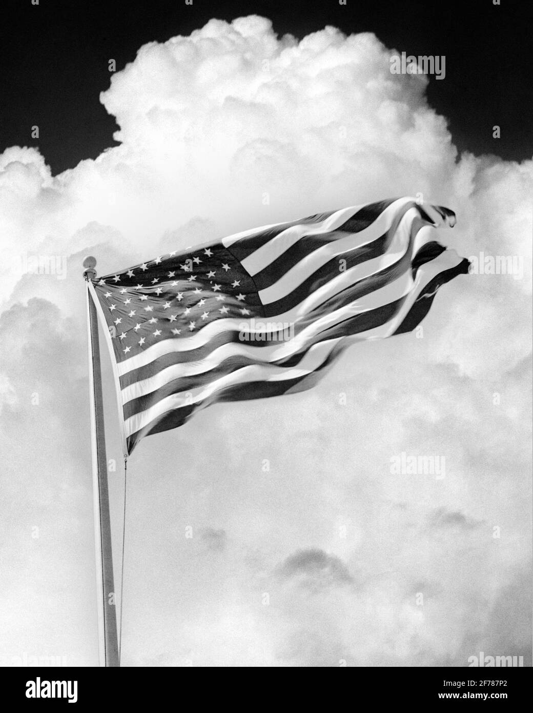 1930s 1940s HIGH BILLOWING CUMULUS CLOUDS BEHIND WAVING IN WIND 48 STAR NATIONAL BANNER OF THE UNITED STATES OF AMERICA - h2417b HAR001 HARS BANNER PROTECTION STRENGTH COURAGE CHOICE EXCITEMENT KNOWLEDGE LEADERSHIP LOW ANGLE POWERFUL PUFFY WORLD WARS INNOVATION PRIDE WORLD WAR WORLD WAR TWO WORLD WAR II OF THE AUTHORITY FLUFFY CONCEPT CONCEPTUAL BILLOWING PATRIOTIC STARS AND STRIPES STYLISH WORLD WAR 2 48 OLD GLORY SYMBOLIC CONCEPTS COOPERATION RED WHITE AND BLUE BLACK AND WHITE COMPOSITION CUMULUS HAR001 OLD FASHIONED REPRESENTATION Stock Photo