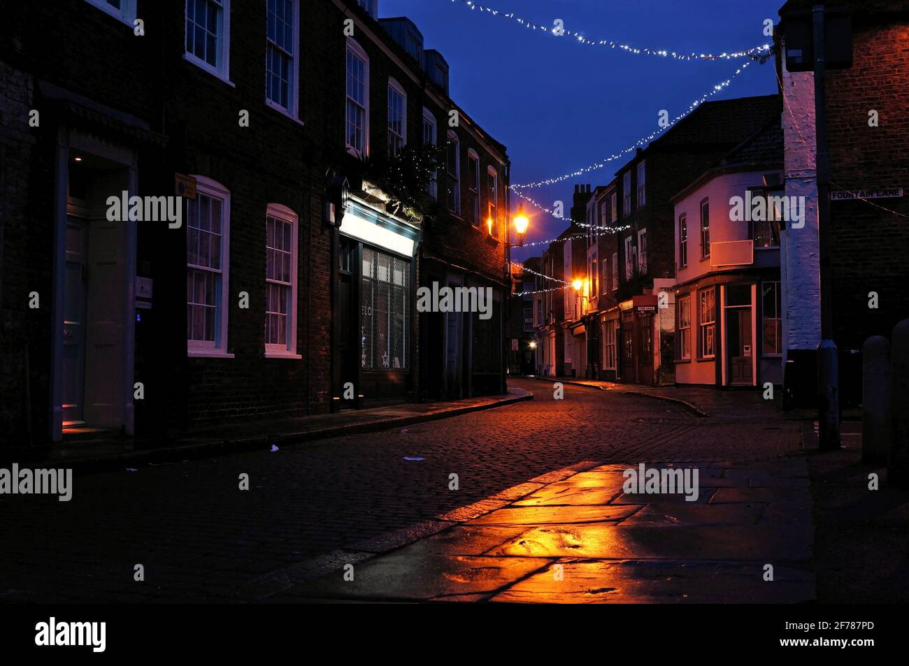 Empty victorian cobbled street on a winter's night with Christmas street lighting. Stock Photo