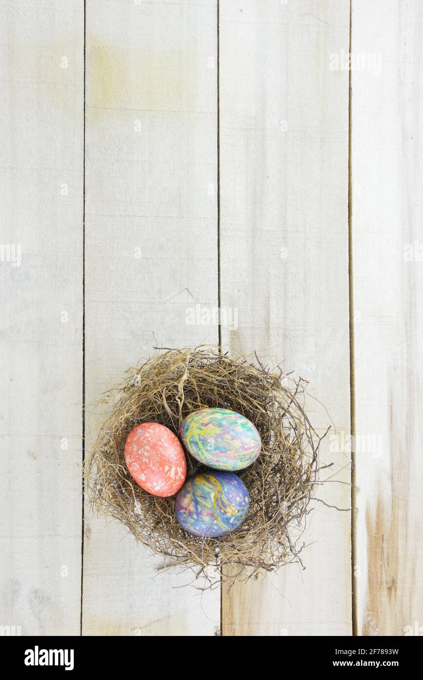 Nest with twigs and colored Easter eggs on wooden table Stock Photo