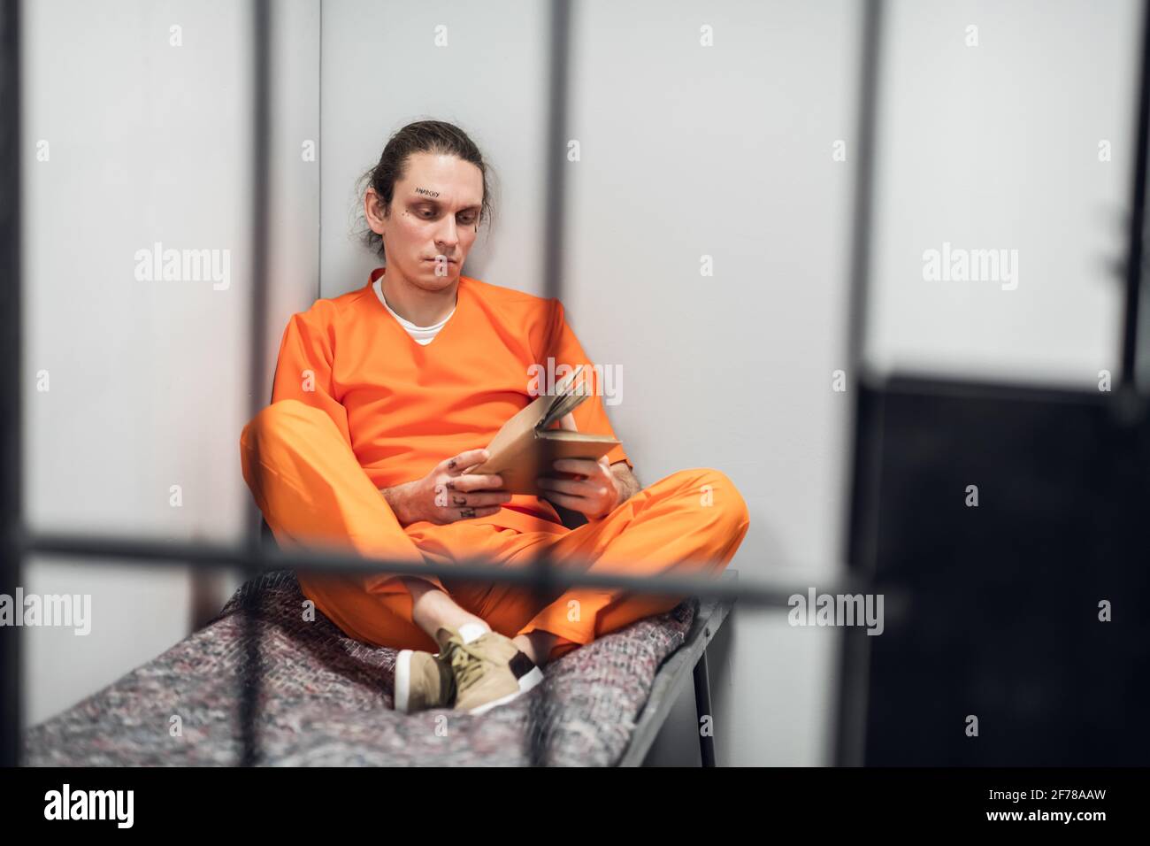 A young inmate with a tattooed face is being remotely trained in a cell ...