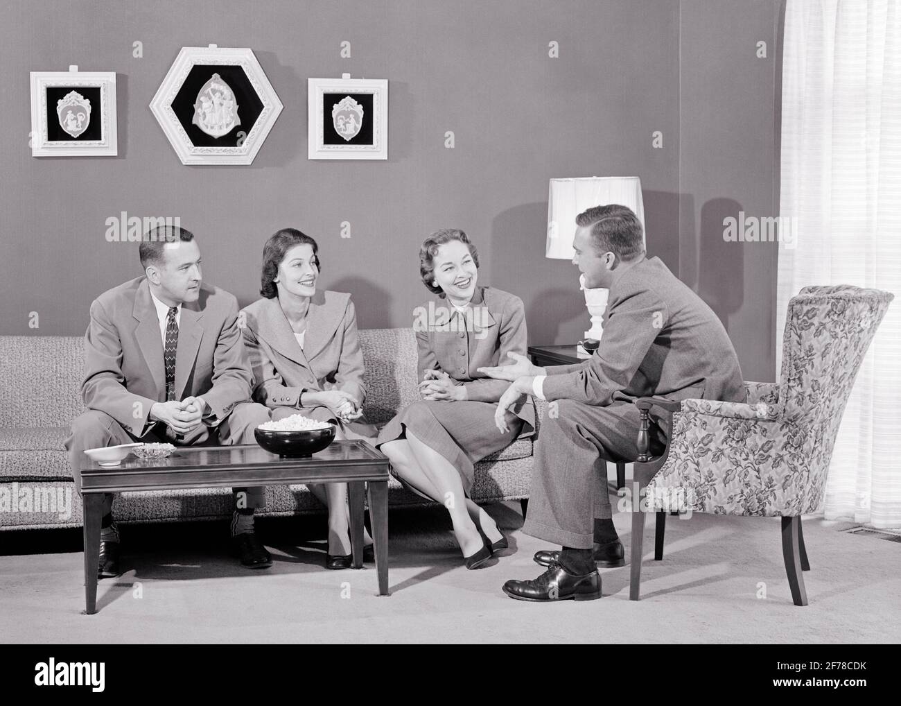1950s TWO COUPLES SITTING LIVING ROOM TALKING SMILING SOCIAL GATHERING CONVERSATION SNACKS ON COFFEE TABLE - s7515 HAR001 HARS NOSTALGIA OLD FASHION CONVERSATION COUCH STYLE COMMUNICATION FRIEND PLEASED JOY LIFESTYLE FEMALES MARRIED SPOUSE HUSBANDS HOME LIFE COPY SPACE FRIENDSHIP HALF-LENGTH LADIES PERSONS MALES B&W GATHERING PARTNER SNACKS SUIT AND TIE CHEERFUL LEISURE SMILES FRIENDLY JOYFUL STYLISH GET-TOGETHER INFORMAL MID-ADULT MID-ADULT MAN MID-ADULT WOMAN TOGETHERNESS WIVES BLACK AND WHITE CAUCASIAN ETHNICITY HAR001 OLD FASHIONED Stock Photo