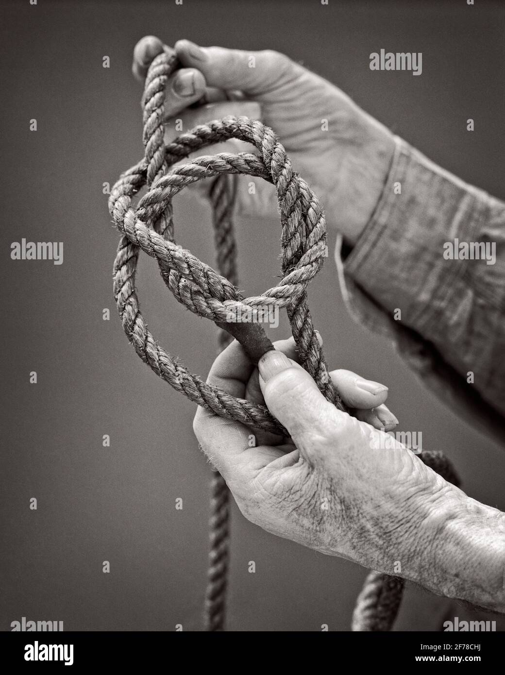 1920s 1930s 1940s BOWLINE KNOT DEMONSTRATED BY ROUGH WORN HANDS OF SENIOR EXPERIENCED MAN SAILOR - s7711 HAR001 HARS PERSONS MALES SYMBOLS ROUGH CONFIDENCE SENIOR MAN SENIOR ADULT B&W OLD AGE OLDSTERS OLDSTER BOTH STRENGTH AND EXPERIENCED CHOICE KNOWLEDGE POWERFUL PRIDE BY OF TO SIMPLE ELDERS KNOT CONCEPT CONNECTION CONCEPTUAL RELIABLE EASY IMPORTANT SYMBOLIC TYING UNTIE CONCEPTS IDEAS PRECISION SECURE SOLUTIONS VIRTUES WORN BASIC BLACK AND WHITE CAUCASIAN ETHNICITY HANDS ONLY HAR001 OLD FASHIONED REPRESENTATION Stock Photo
