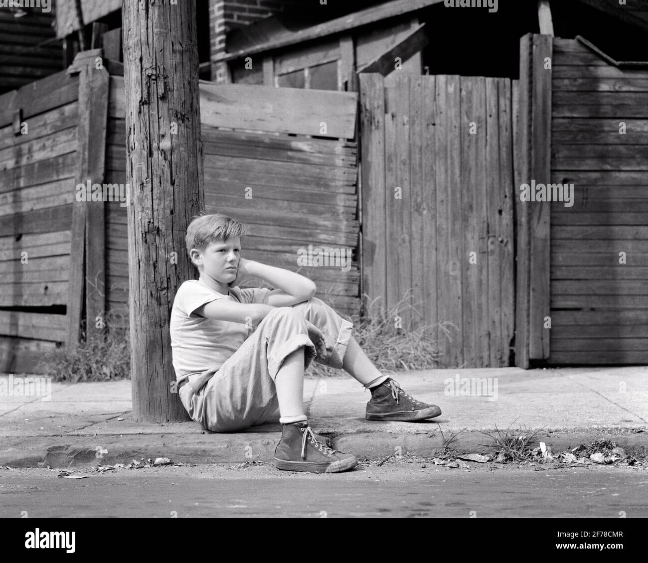 1940s 1950s SAD POOR SINGLE BOY SITTING ON CITY STREET CURB LEANING AGAINST TELEPHONE POLE WEARING DIRTY HIGH TOP SNEAKERS - w1546 HAR001 HARS POLE LOST LIFESTYLE MOODY POOR HOME LIFE COPY SPACE AGAINST FULL-LENGTH MALES RISK SNEAKERS TROUBLED B&W CONCERNED SADNESS DREAMS NEIGHBORHOOD WELFARE LOW ANGLE ABANDONED MOOD GLUM CURB DISADVANTAGED DISAFFECTED DISAPPOINTED DISCONNECTED IMPOVERISHED JUVENILES MISERABLE NEGLECTED PRE-TEEN PRE-TEEN BOY SLUM BLACK AND WHITE CAUCASIAN ETHNICITY DISTRAUGHT HAR001 OLD FASHIONED Stock Photo