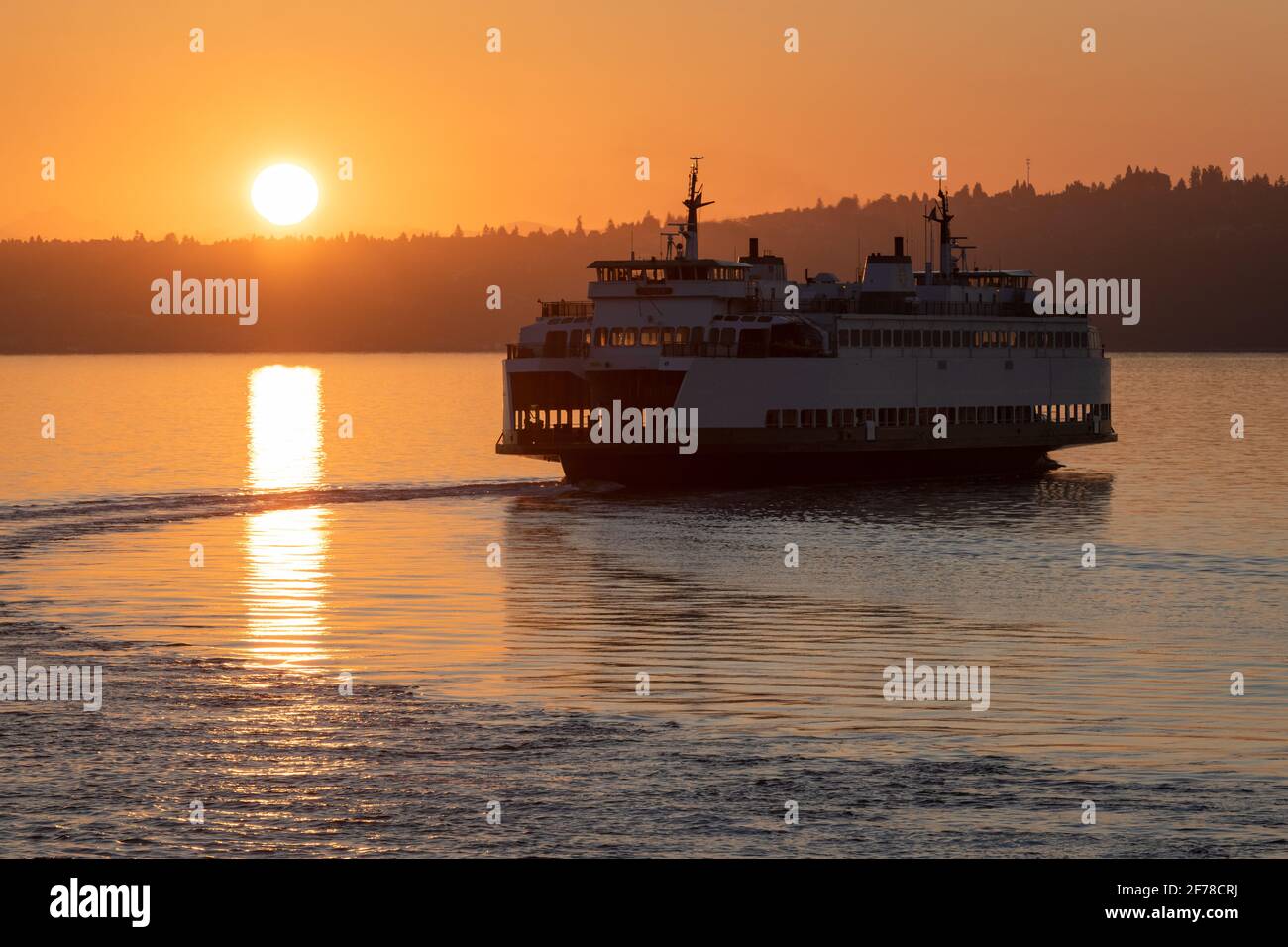 Vashon Island, WA, USA - July 18, 2018; MV Sealth leaves Vashon Island backlit by a brilliant orange rising sun on a scheduled ferry sailing Stock Photo