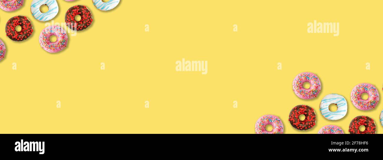 Delicious colorful donuts on yellow background, flat lay. Space for text Stock Photo