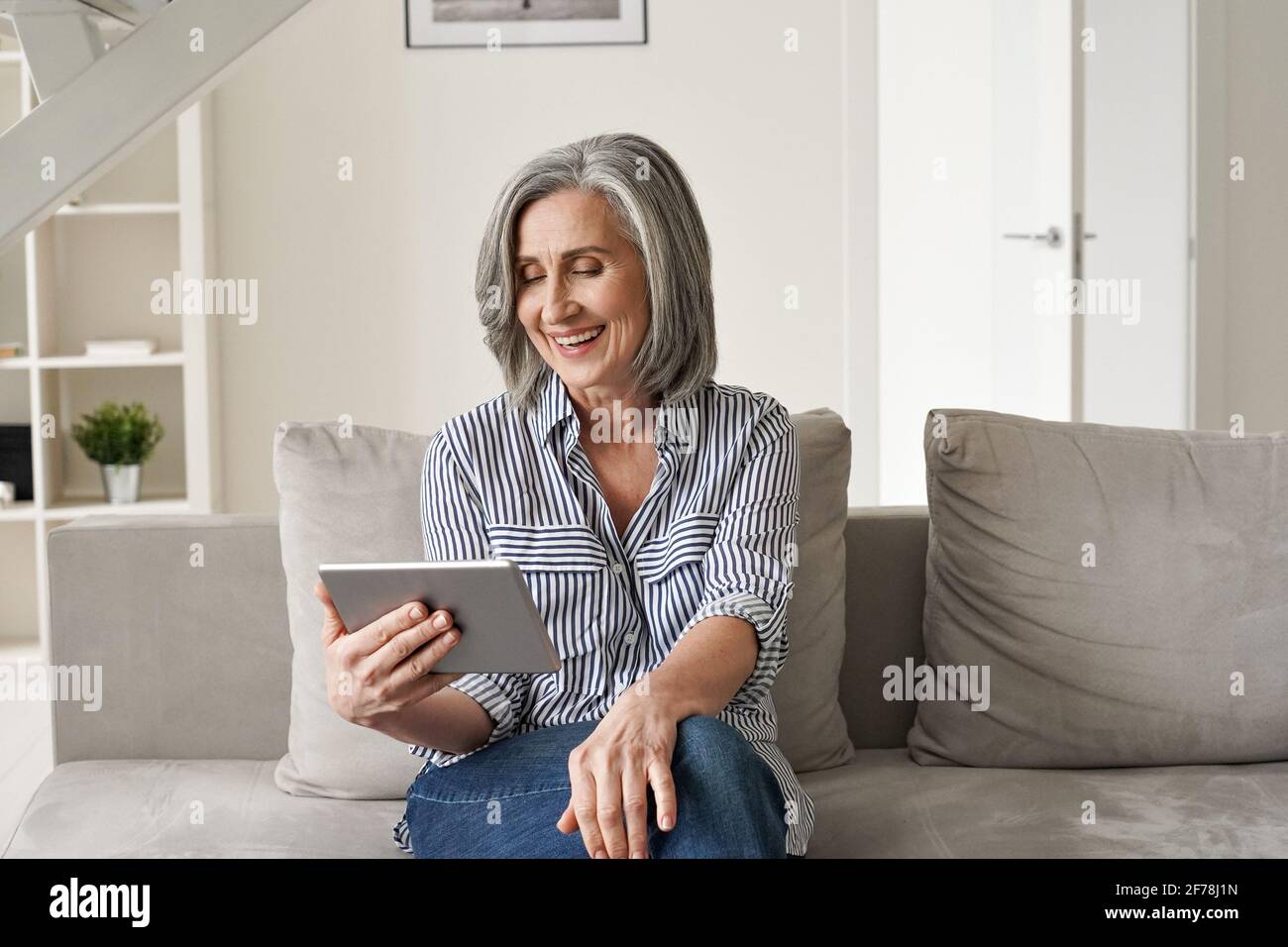 Happy old woman using digital tablet having virtual online meeting at home. Stock Photo