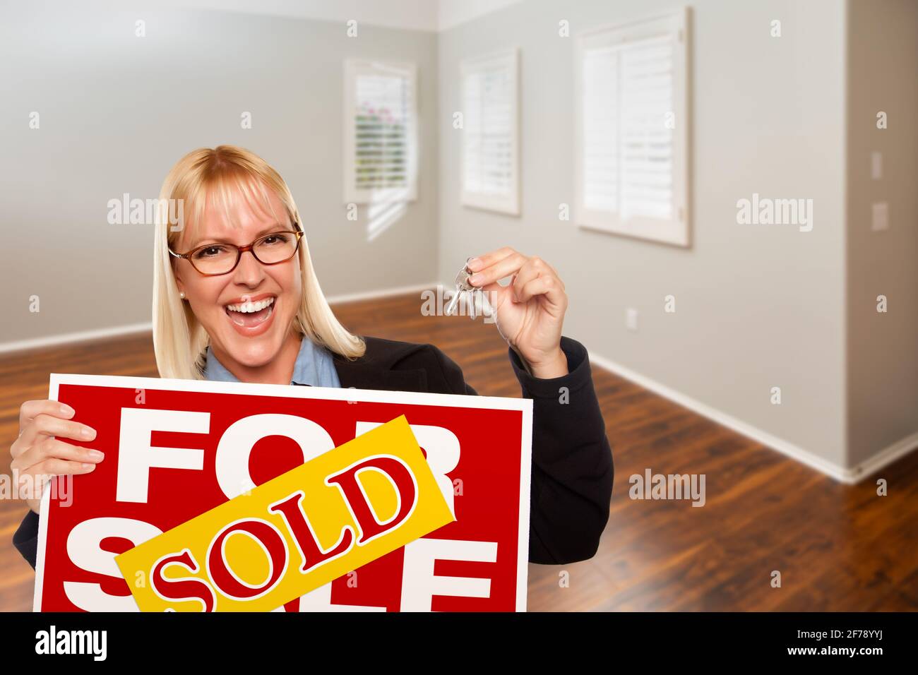 Woman with Sold For Sale Real Estate Sign and Keys In Empty Room of New ...