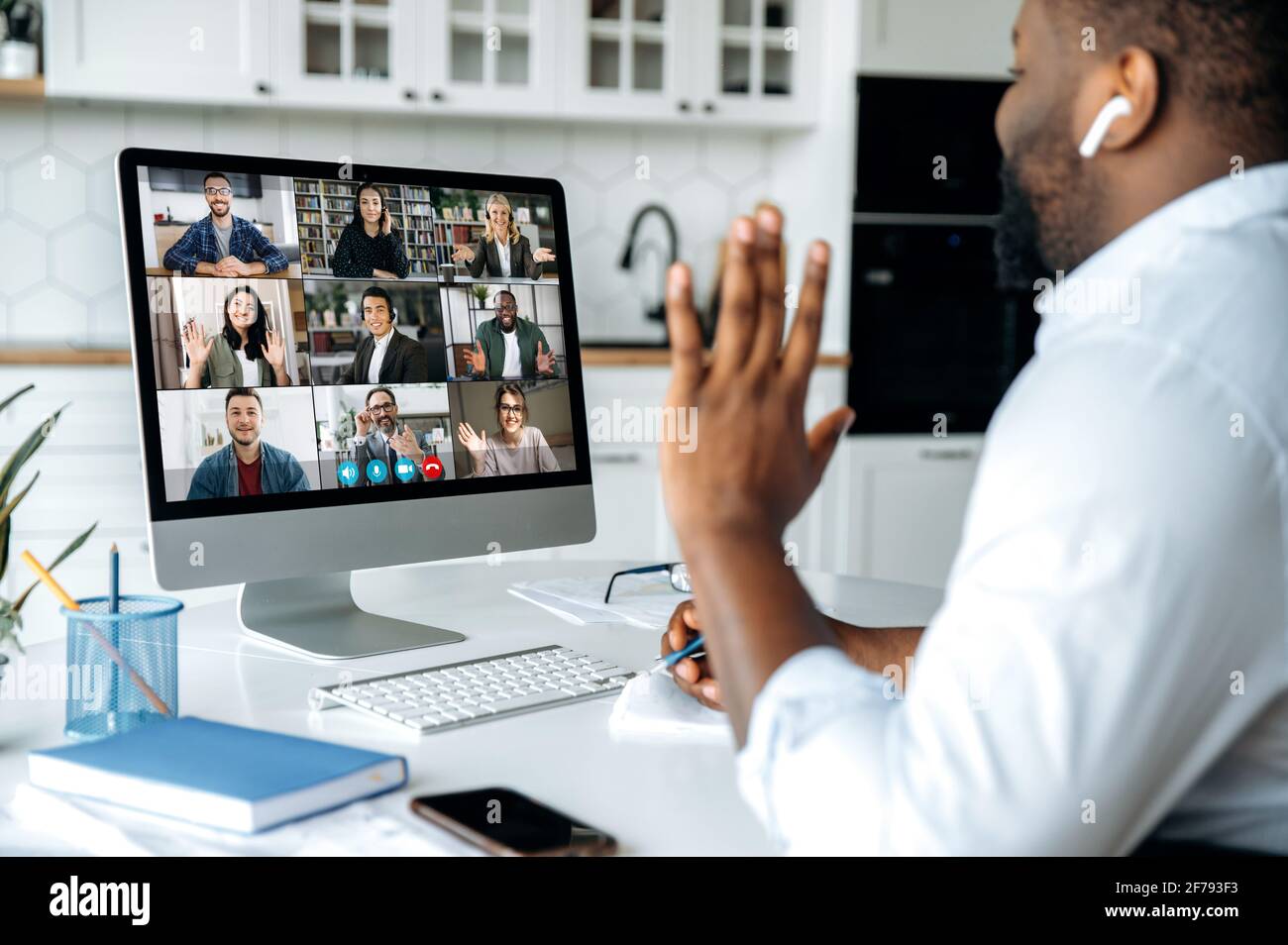 Video call, online conference. Over shoulder view of african american man at computer screen with multinational group of successful business people, virtual business meeting, work from home concept Stock Photo