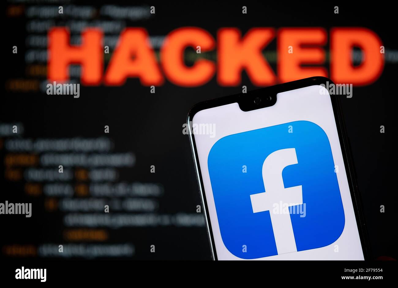 Facebook app logo seen on the smartphone and blurred HACKED word with a brute force script on the blurred background. Concept for facebook data breach Stock Photo