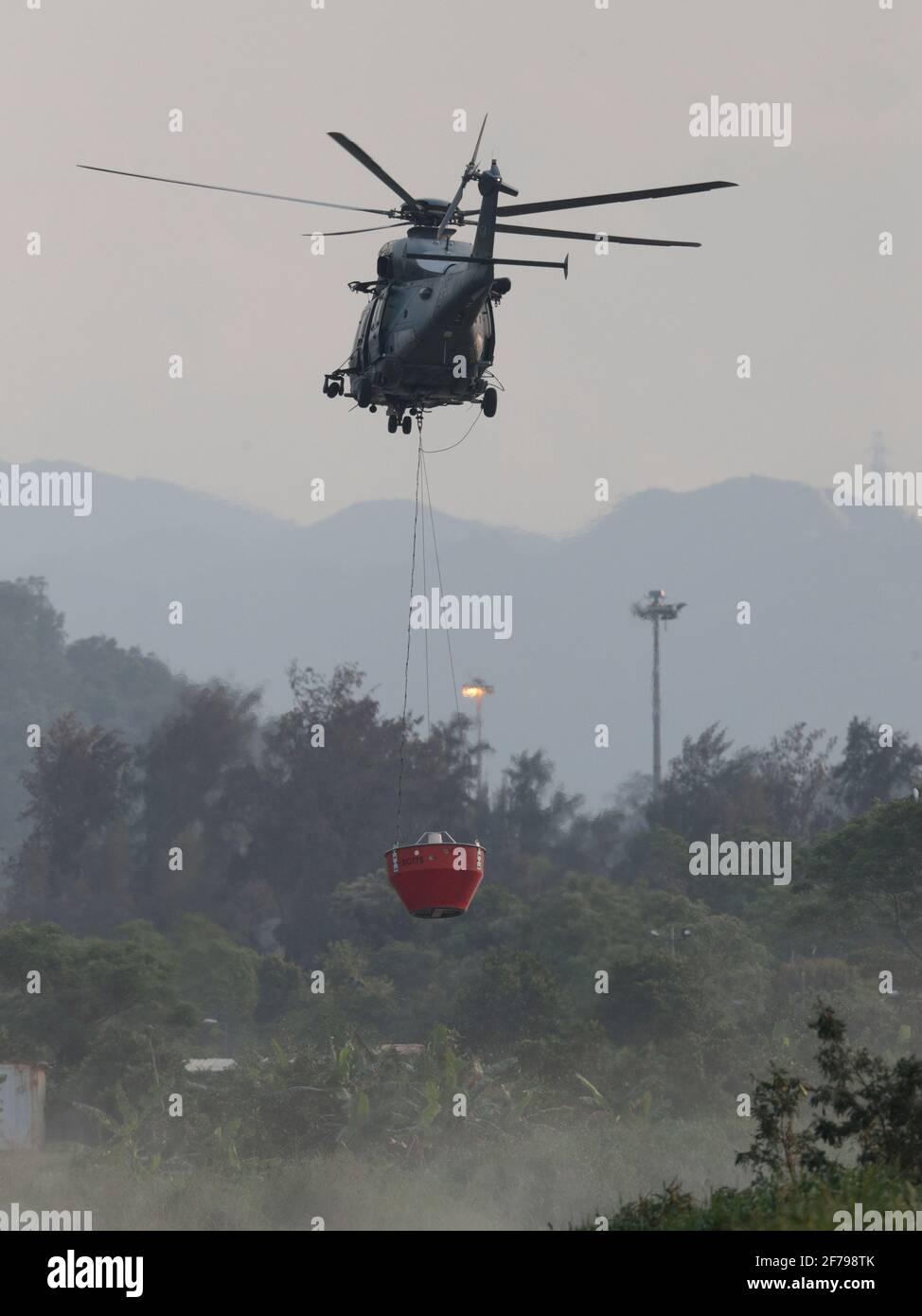 Government Flying Services helicopter with fire-bucket, Shenzhen River loop, New Territories, Hong Kong, China 2nd April 2021 Stock Photo
