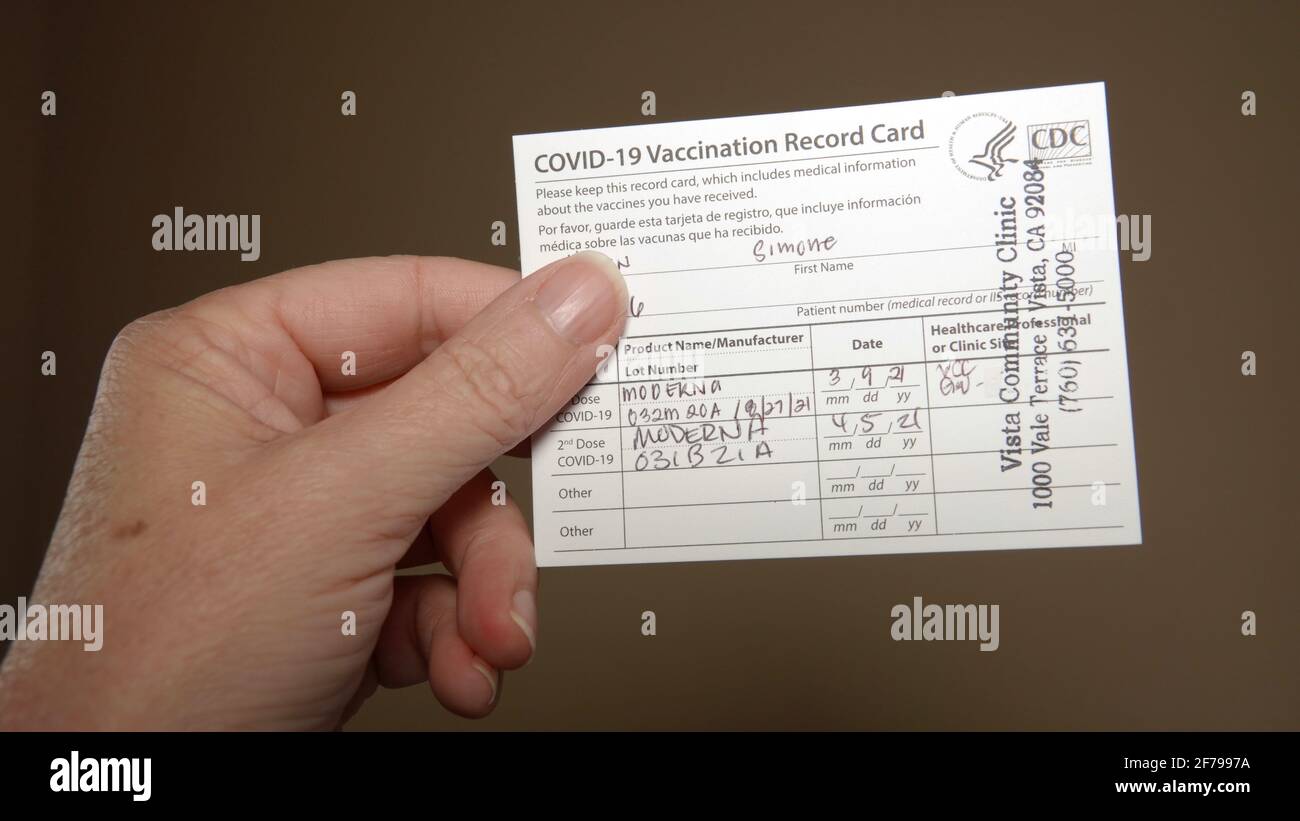 Older woman's hand holding up a completed Covid 19 Vaccination Record Card. Illustrative Editorial taken in Vista, CA  USA on April 4, 2021. Stock Photo