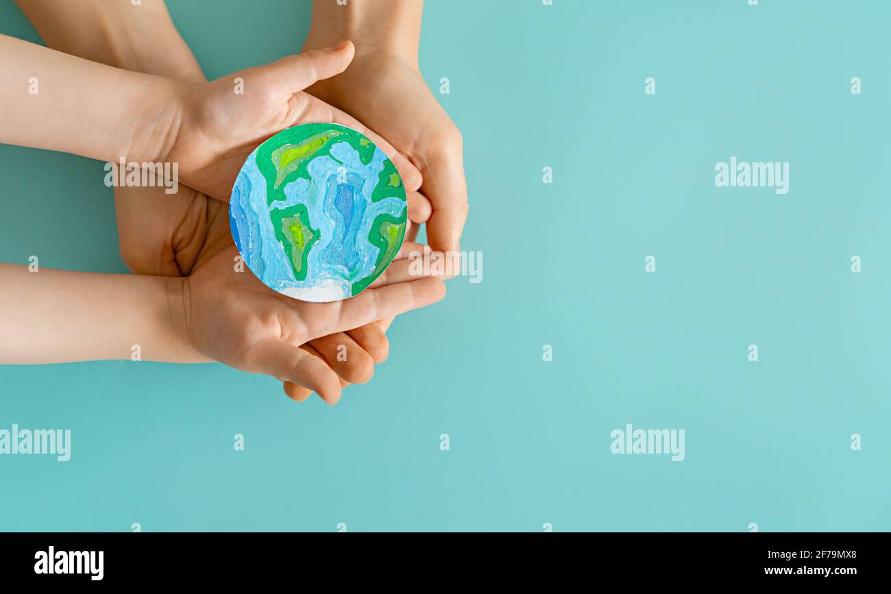 Child and adult holding planet in hands on teal background. Earth day ...