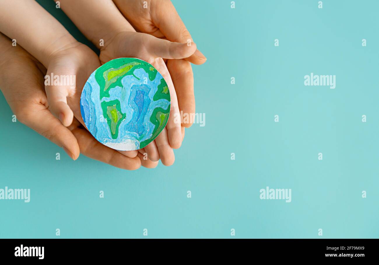 Child and adult holding planet in hands on teal background. Earth day ...