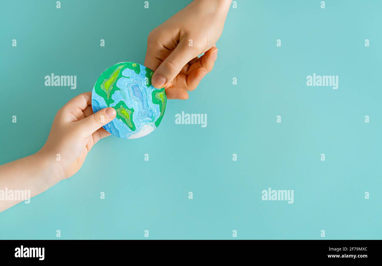 Child and adult holding planet in hands on teal background. Earth day ...