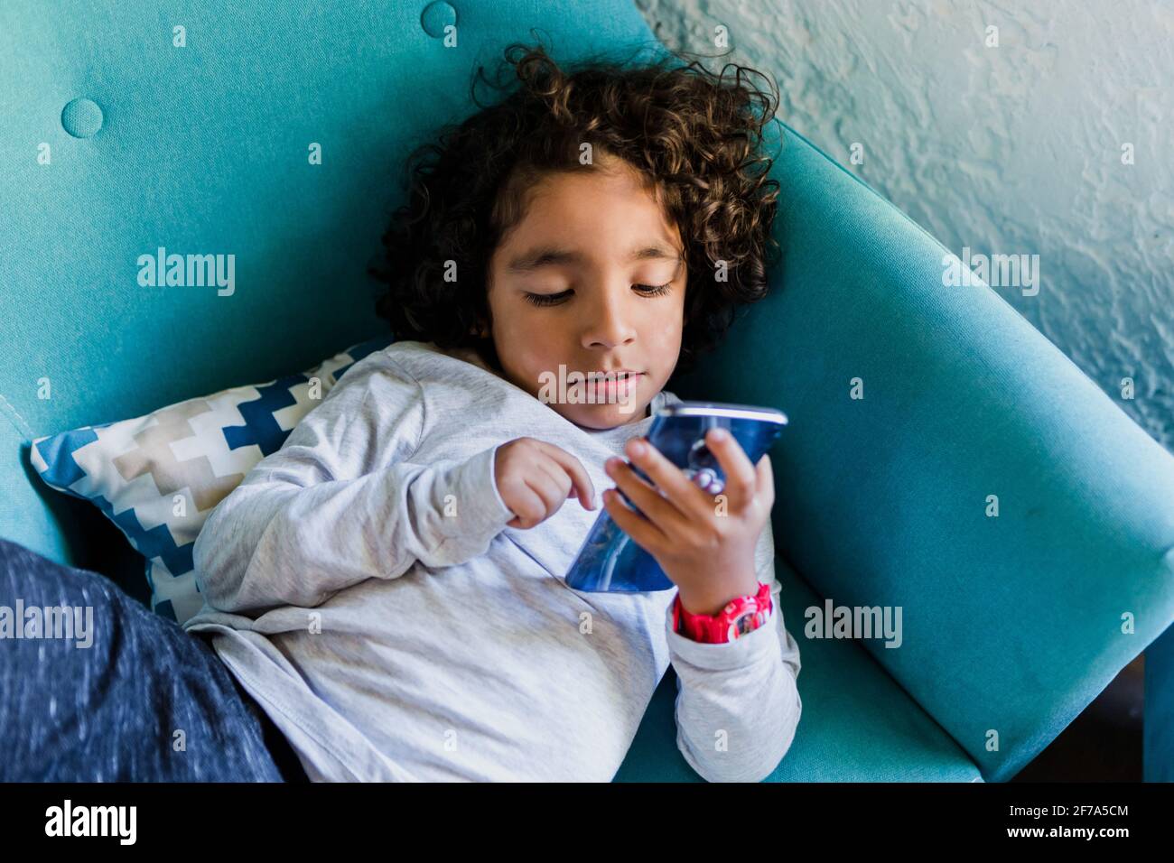 portrait of latin child holding a smartphone at home in Mexico city Stock Photo