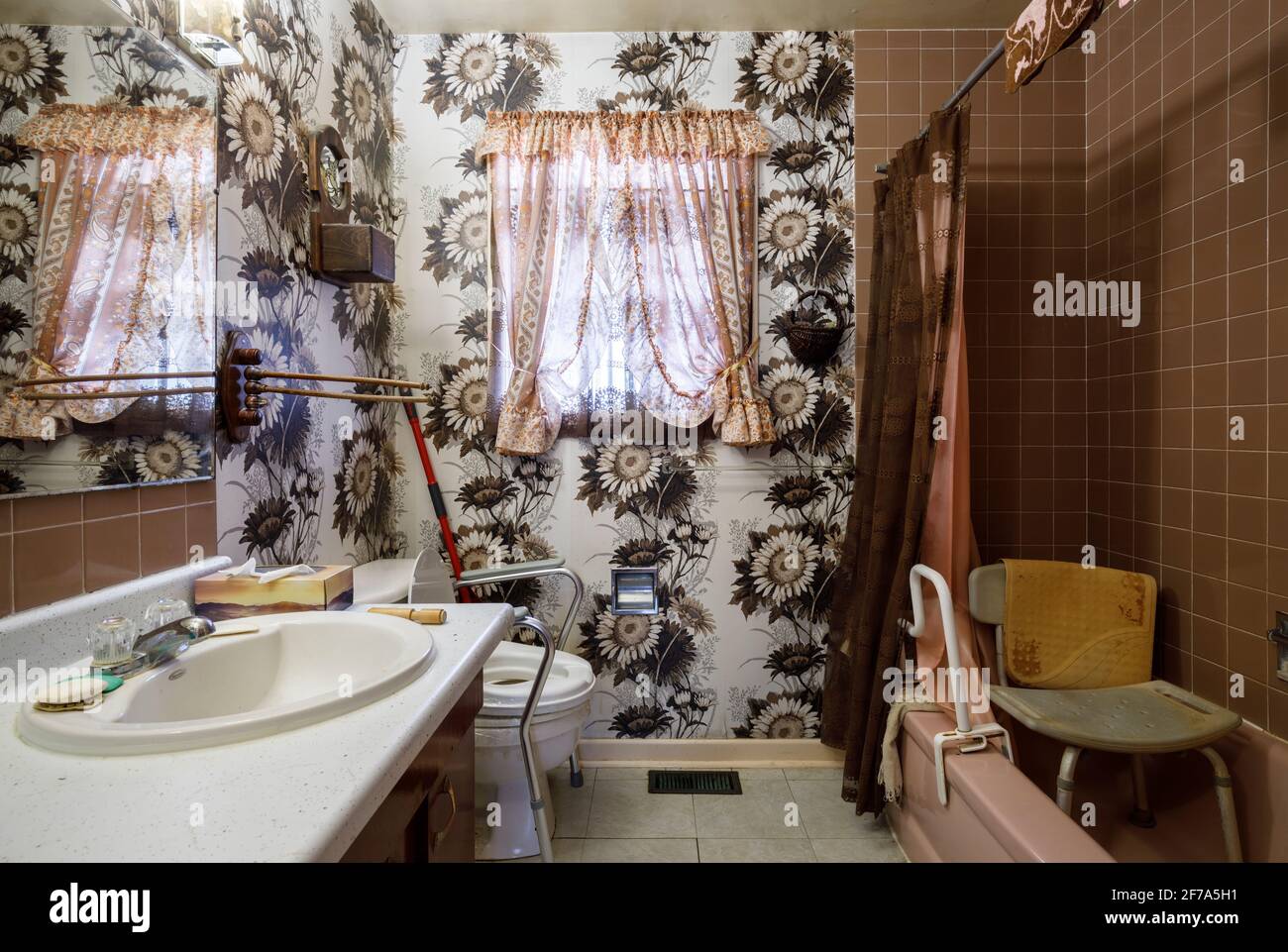 A retro bathroom with a raised toilet seat, shower chair and a grab bar used by elderly people. Stock Photo