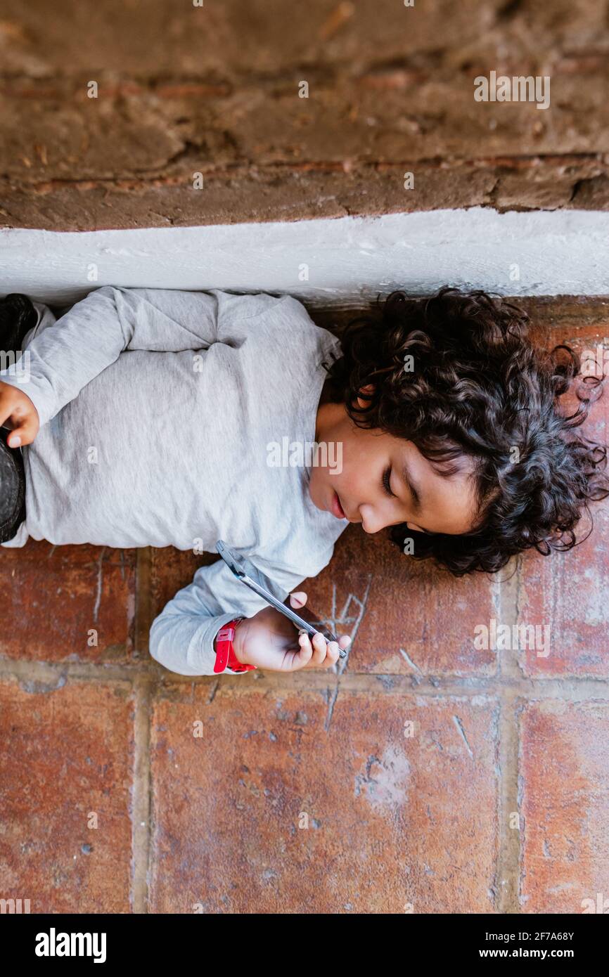 portrait of latin child holding a smartphone at home in Mexico city Stock Photo