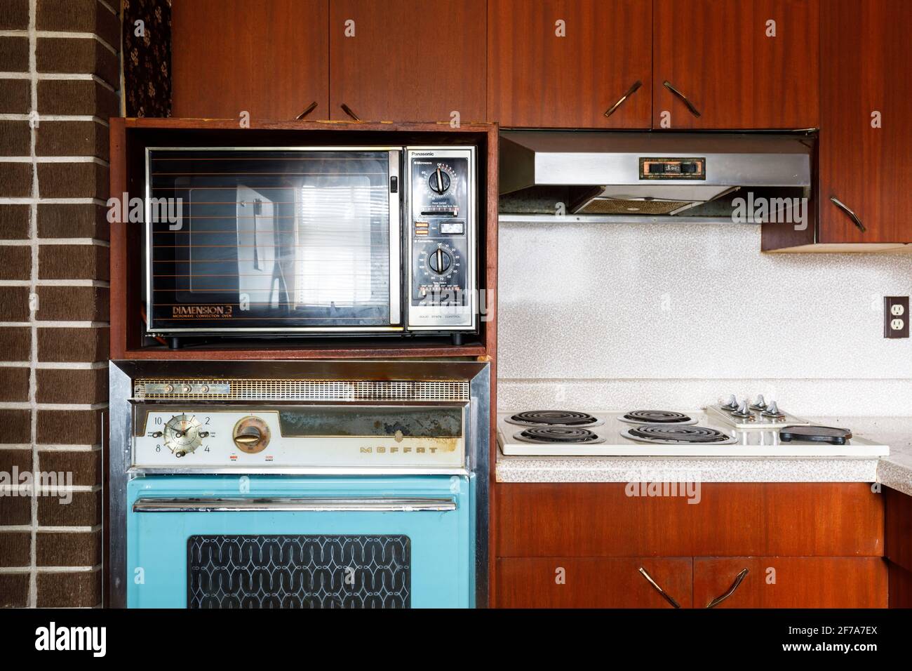 A 1960s Moffat 69 wall oven, 1980s Panasonic Dimension 3 microwave/convection oven and Moffat 40 built-in stovetop inside a retro kitchen. Stock Photo