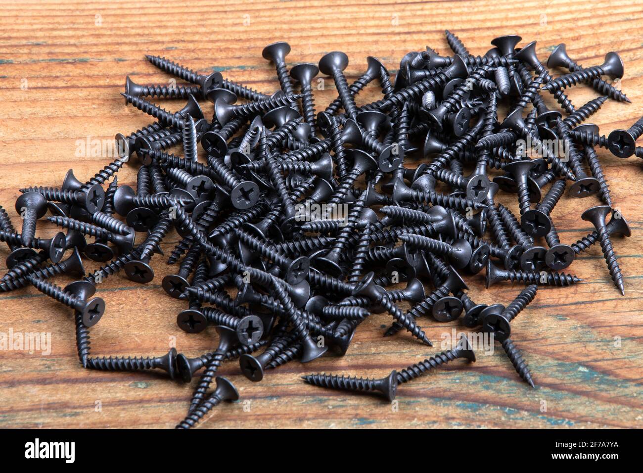 Black screws on a wooden texture background. Screws for plasterboard