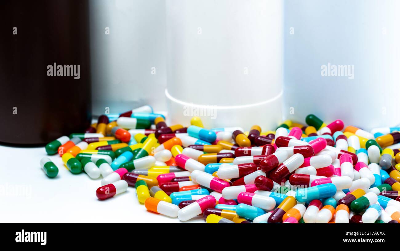 Pile of colorful antibiotic capsule pills on blur plastic drug bottle. Antibiotic drug resistance. Antibiotic drug overuse. Pharmaceutical industry. Stock Photo