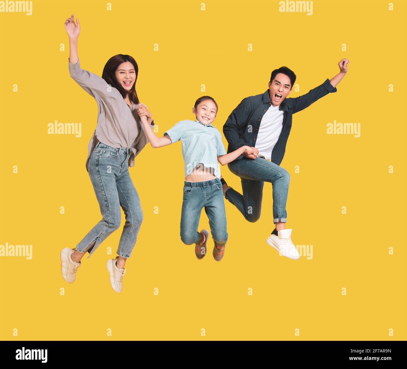 Happy young family with one child jumping together Stock Photo