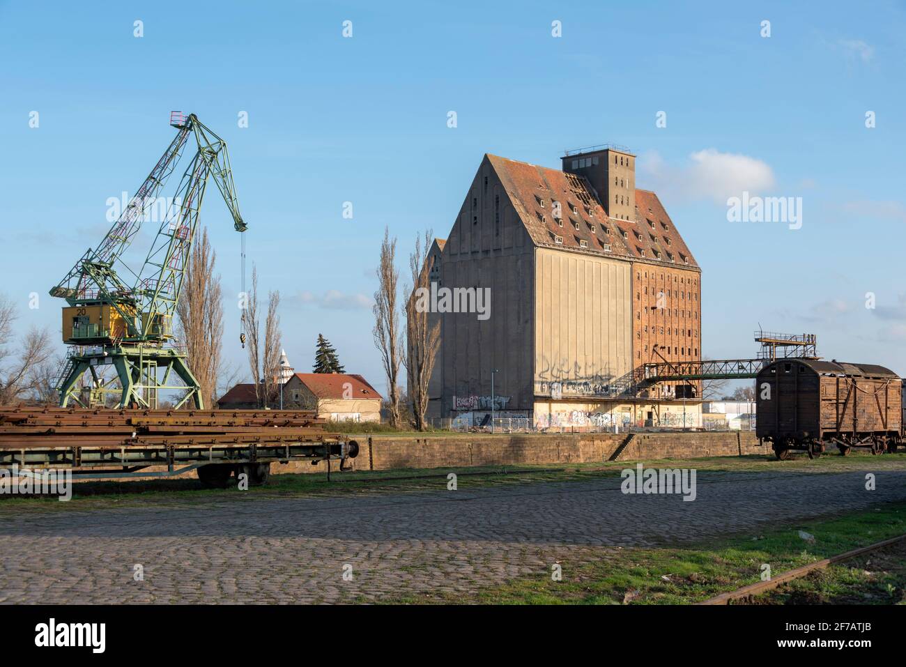 Germany, Saxony-Anhalt, Magdeburg, old commercial harbour with harbour crane, silo, passenger train. Stock Photo