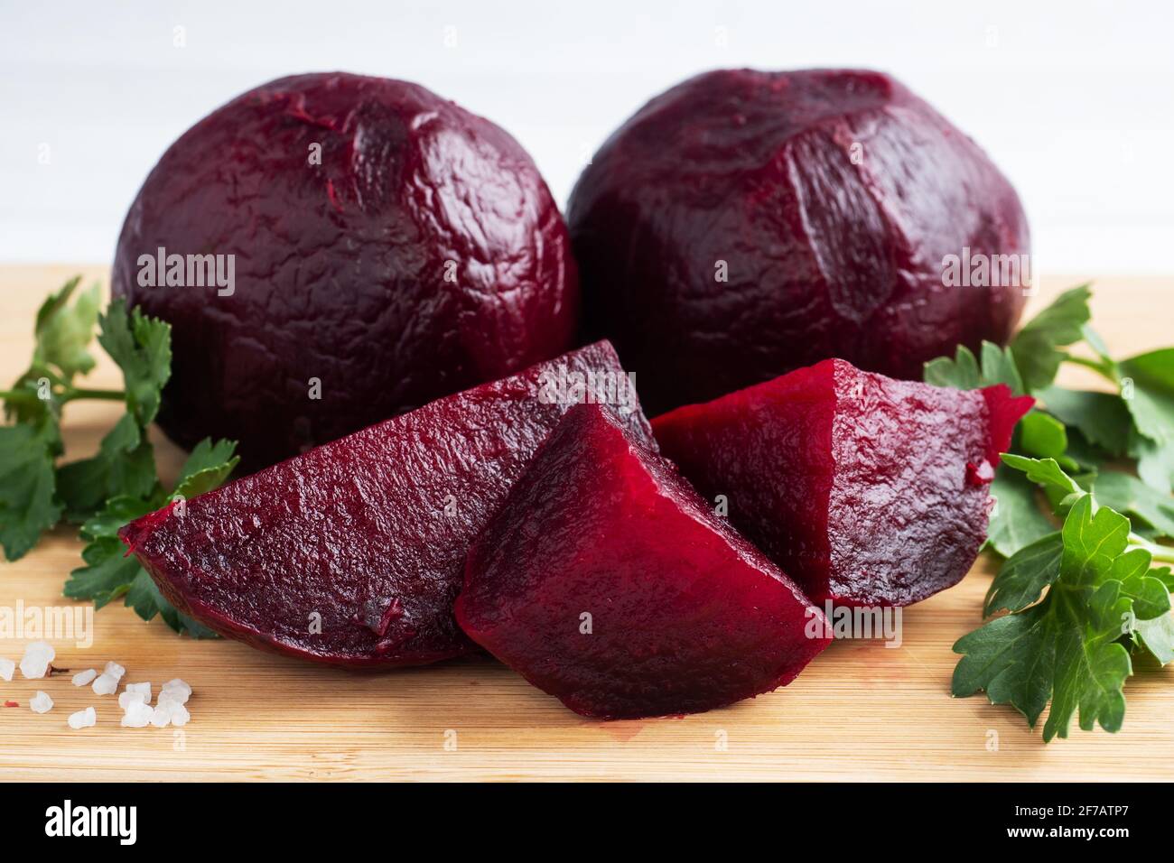 Boiled beets whole and cut on a cutting Board with parsley leaves on a white background. Copy space, Stock Photo
