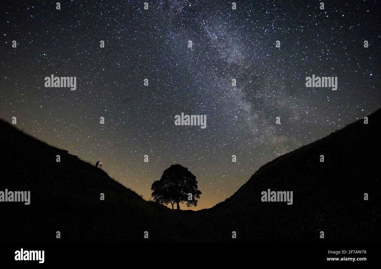 File photo dated 25/08/19 of a photographer lining up a shot on a clear night under the Milky Way at Sycamore Gap on Hadrians Wall in Northumberland. Light pollution levels were much lower at the start of 2021 when the UK was in lockdown, compared with a year before, a nationwide star count has found. Issue date: Saturday April 6, 2019. Stock Photo
