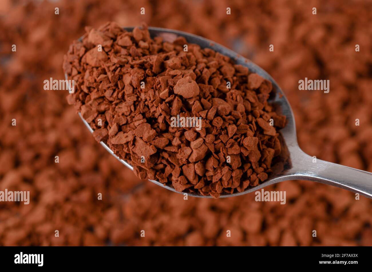 Instant coffee granules lying on the surface. The spoon contains dry