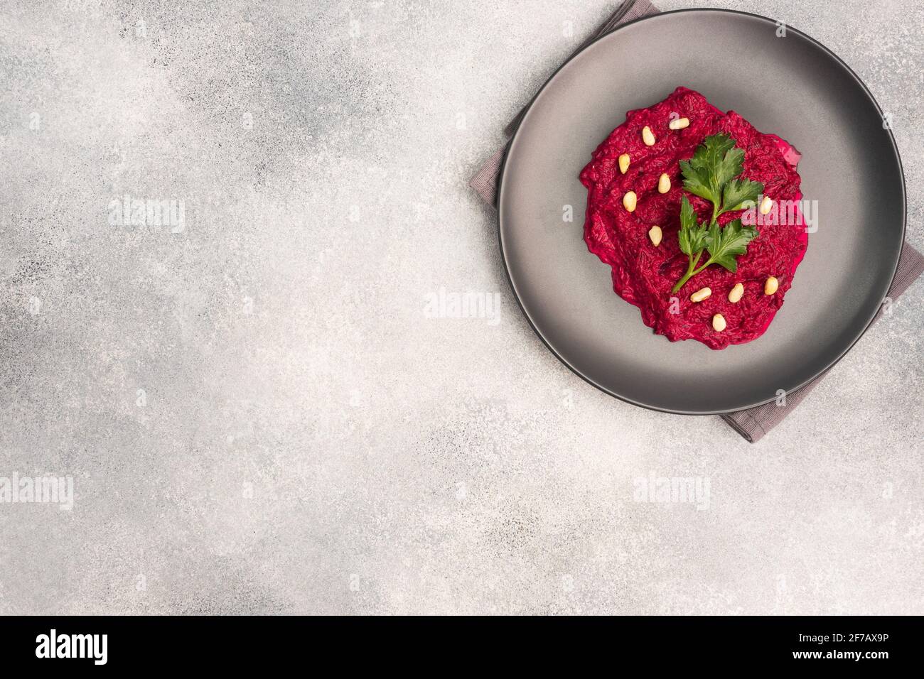 Salad of grated beetroot pine nuts and parsley with cream sauce on a plate top view copy space Stock Photo