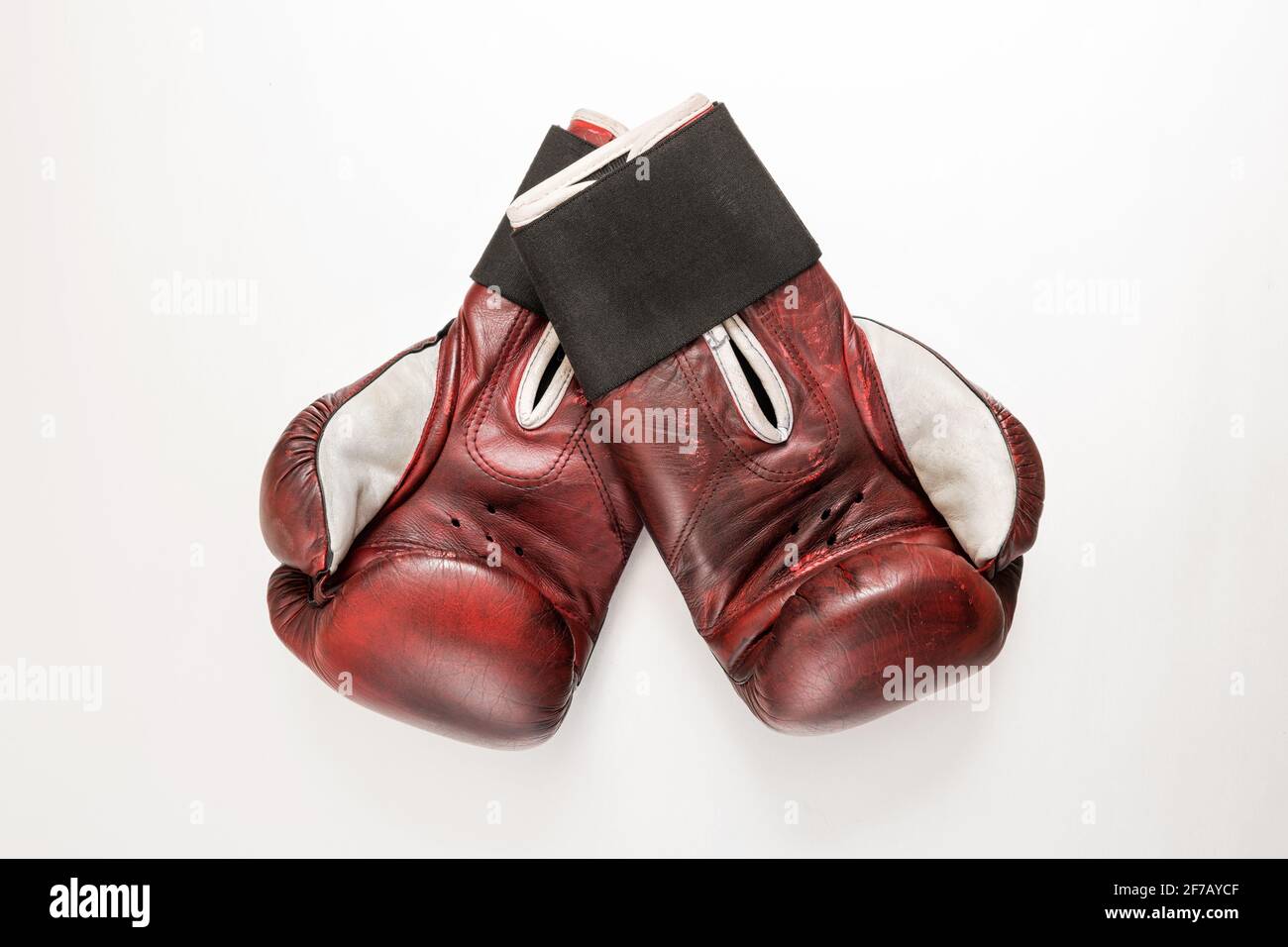 Pair of vintage maroon leather boxing gloves on a white background with the palms facing up to