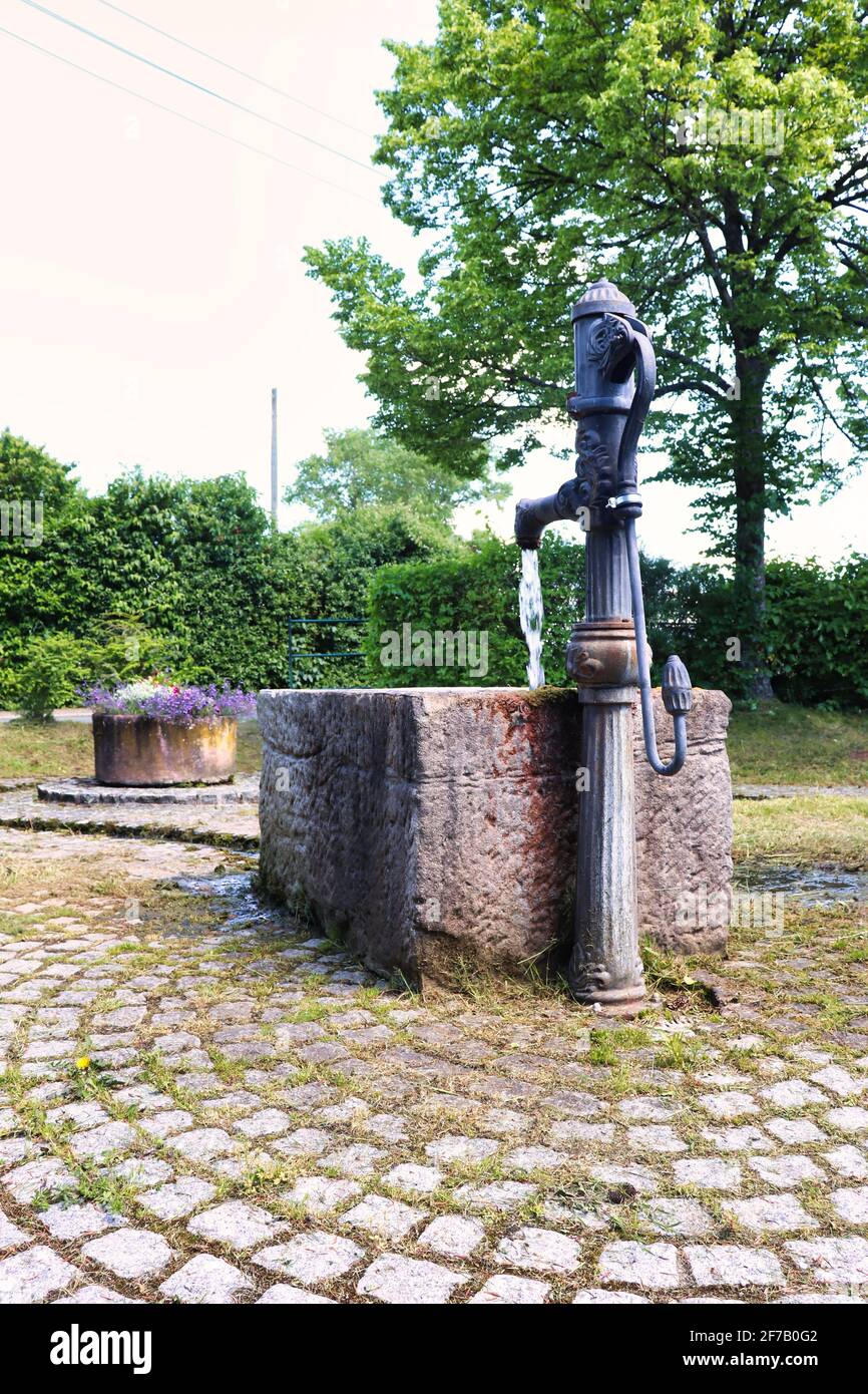 Water Flowing Out Of A Water Pump Fountain In A Park In Winnweiler water-flowing-out-of-a-water-pump-fountain-in-a-park-in-winnweiler