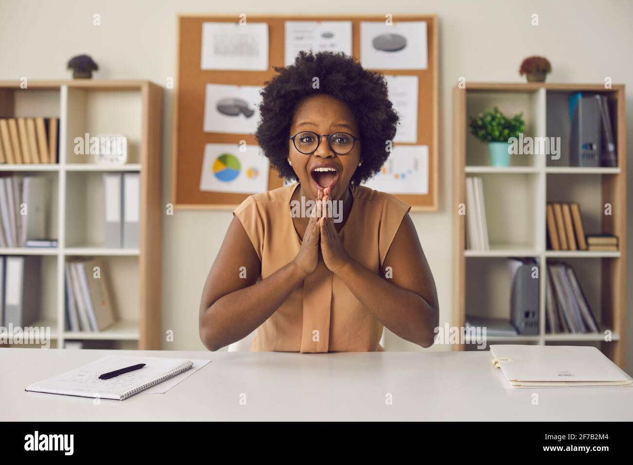 Woman sitting in the office and rejoices at the news during a video call about getting a new job. Stock Photo