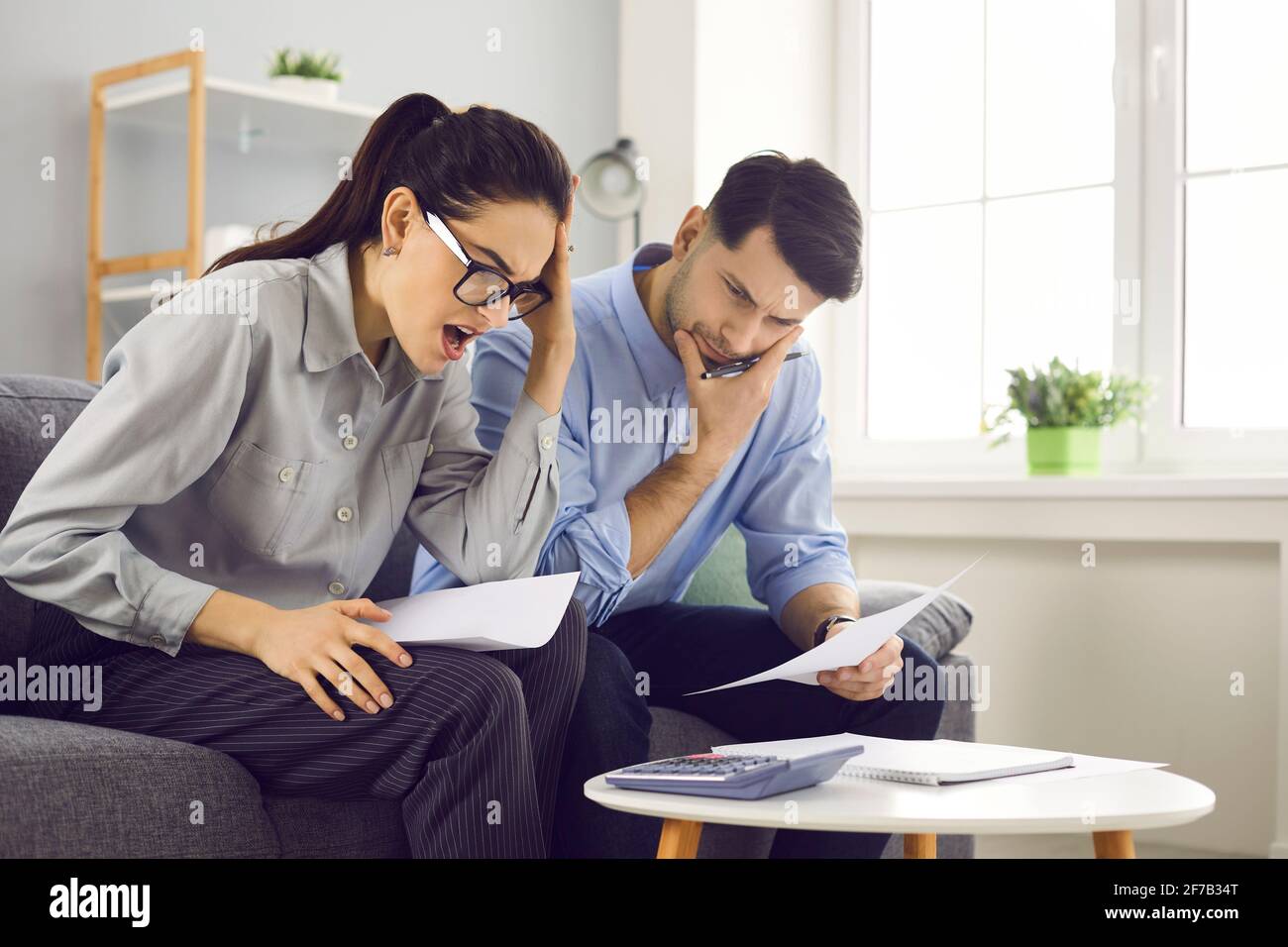 Stressed young couple checking analyzing family bills calculating taxes at home Stock Photo