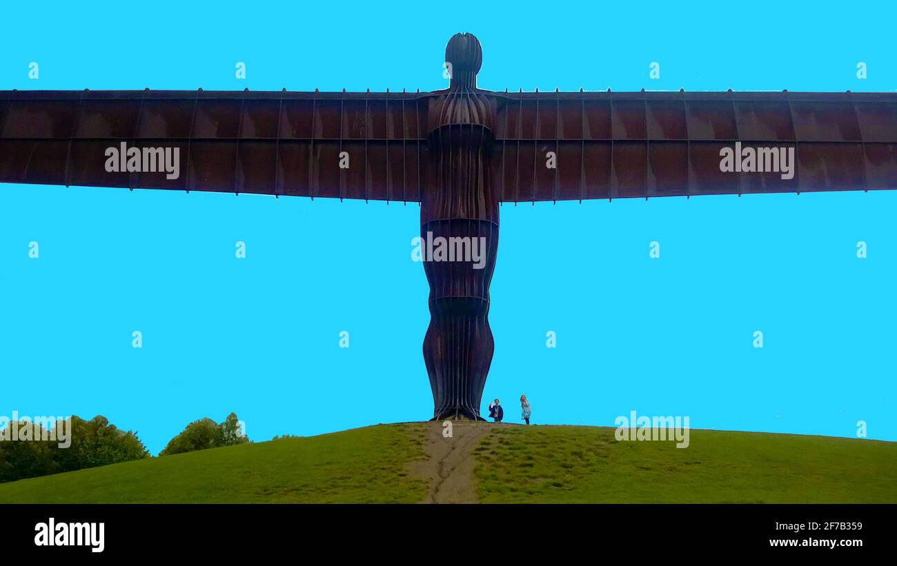'Angel of the North' giant scupture in 2017 - blue sky . Children beneath it give a sense of its size. ----- The iconic scupture (The largest in Britain) was designed by Antony Gormley and built by  Hartlepool Steel Fabrications Ltd using  COR-TEN weather-resistant steel and was completed in 1998. It's located near to  Gateshead, Tyne and Wear, England and is now recognised now as both a landmark and  a symbol of the north eastern area of England and its industrial heritage. Efforts to have the sculpture to be officially listed  as of historic interest  have so far been unsuccessful. Stock Photo