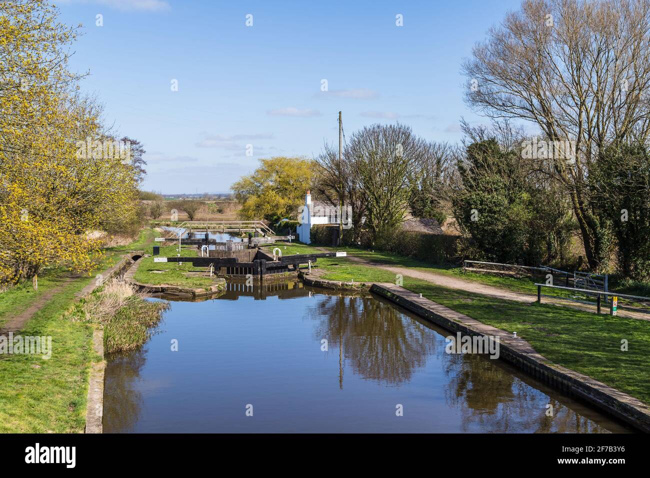 A pretty white cottage next to a quiet lock on the Rufford branch the Leeds Liverpool Canal near Burscough, Lancashire in April 2021. Stock Photo