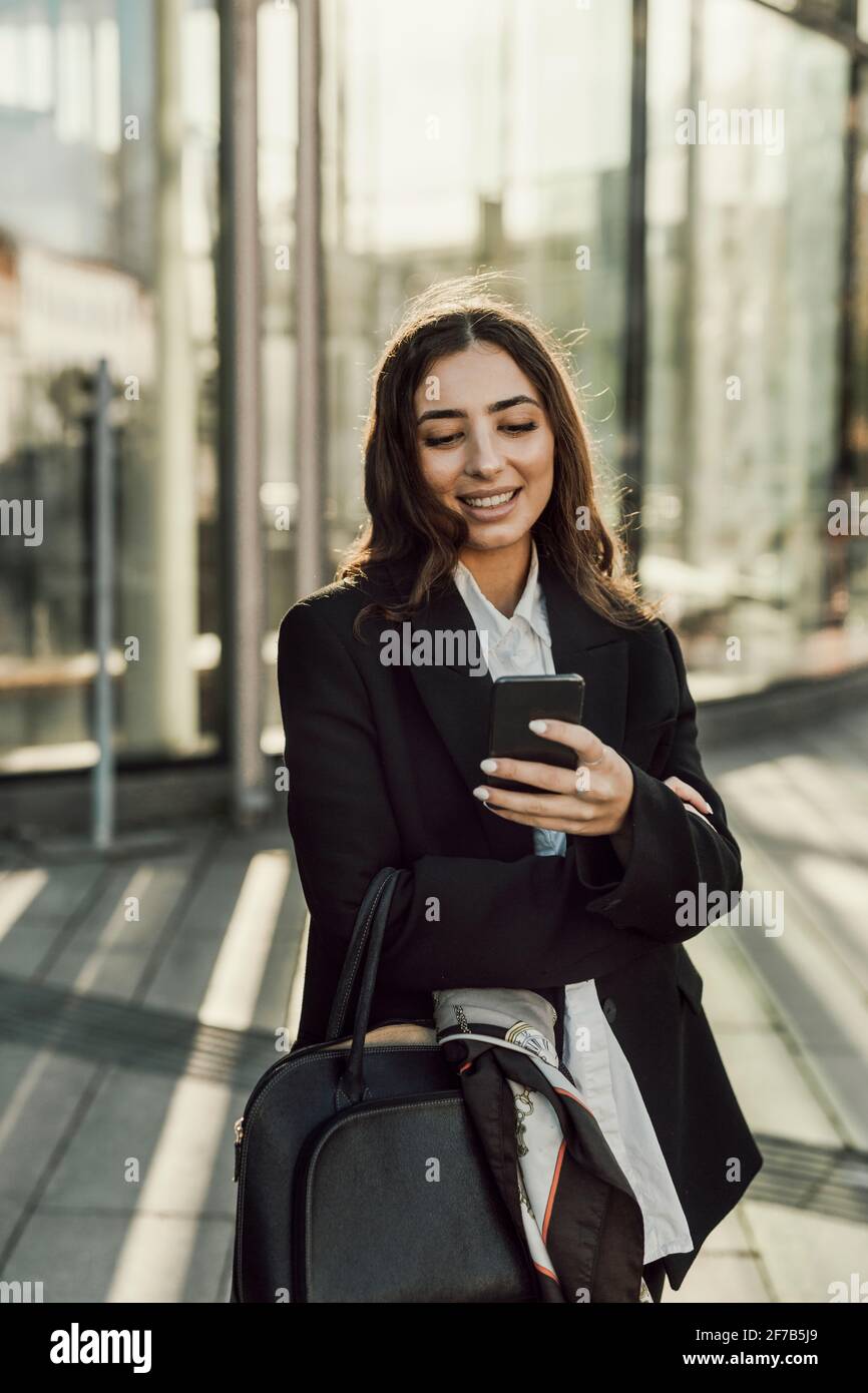 Smiling businesswoman checking cell phone Stock Photo