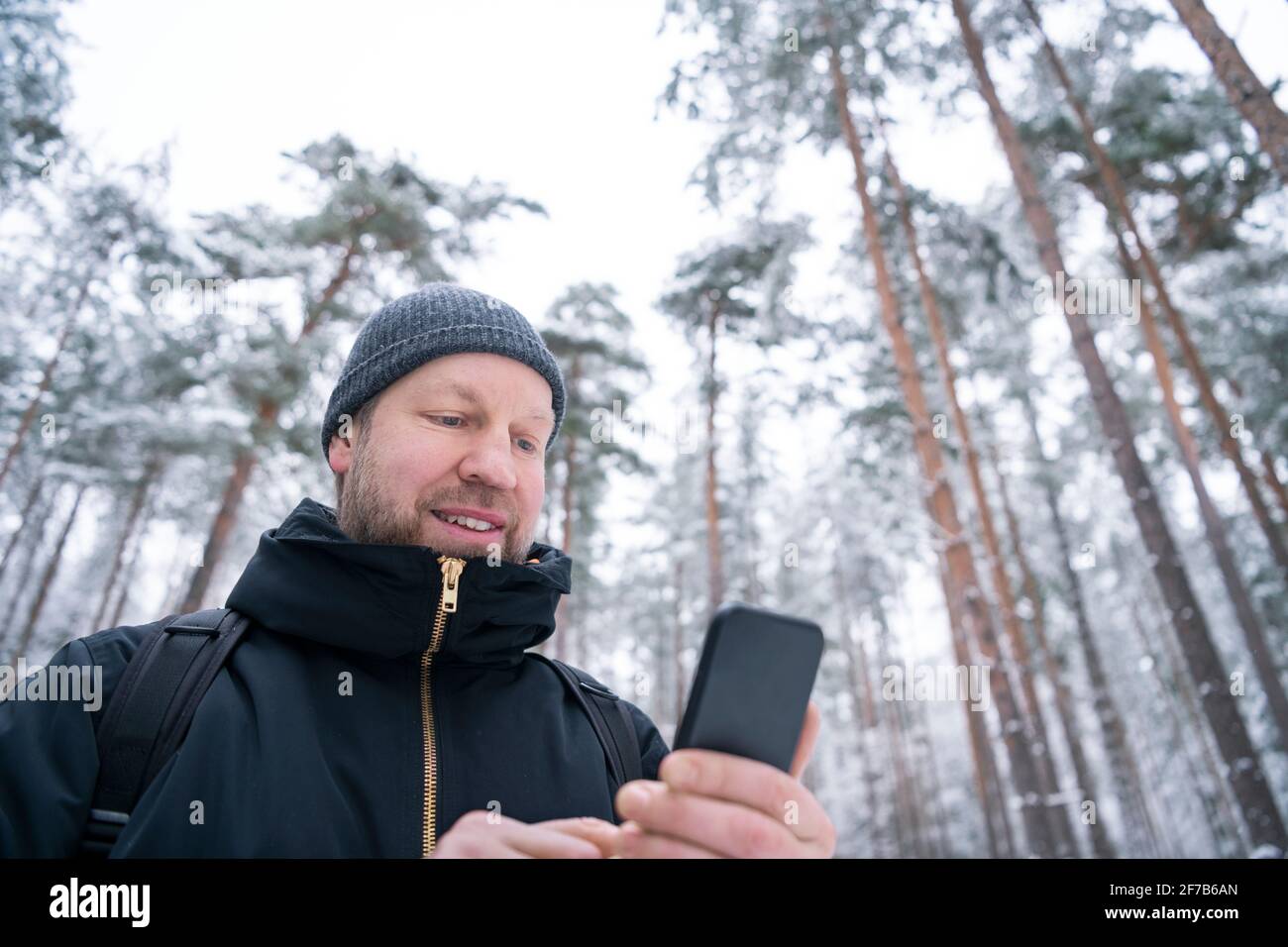Man using smart phone in winter forest Stock Photo