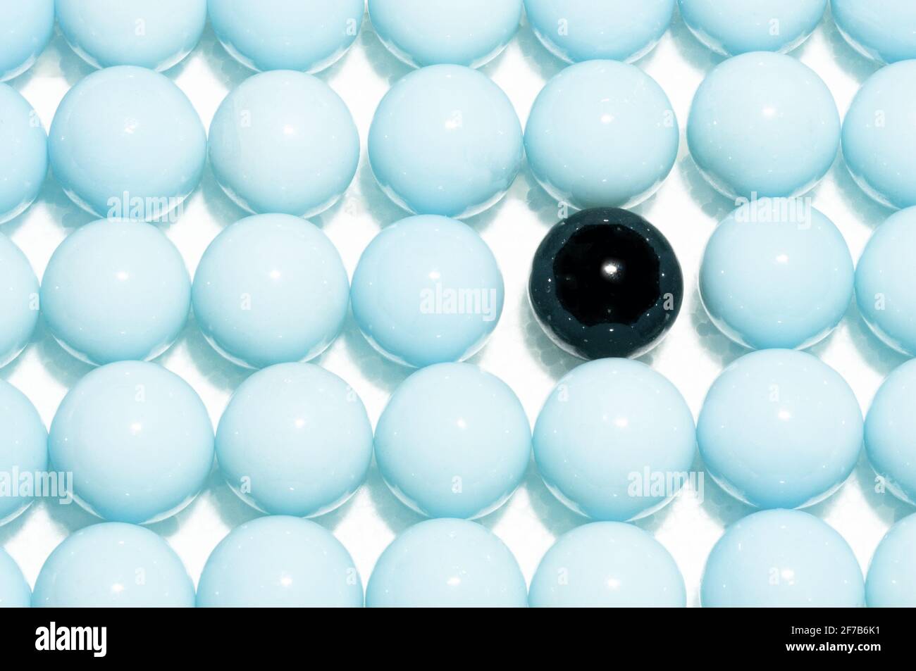 Lone black pearl in white glass spheres background Stock Photo