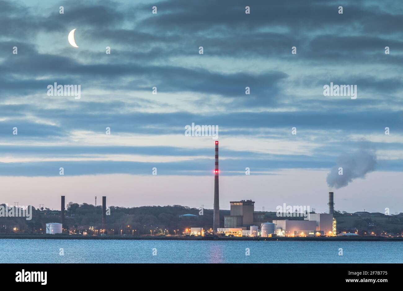 Aghada, Cork, Ireland. 06th April, 2021. A waning Moon begining to rise before dawn over the ESB generating station in Aghada, Co. Cork, Ireland. - Credit; David Creedon / Alamy Live News Stock Photo