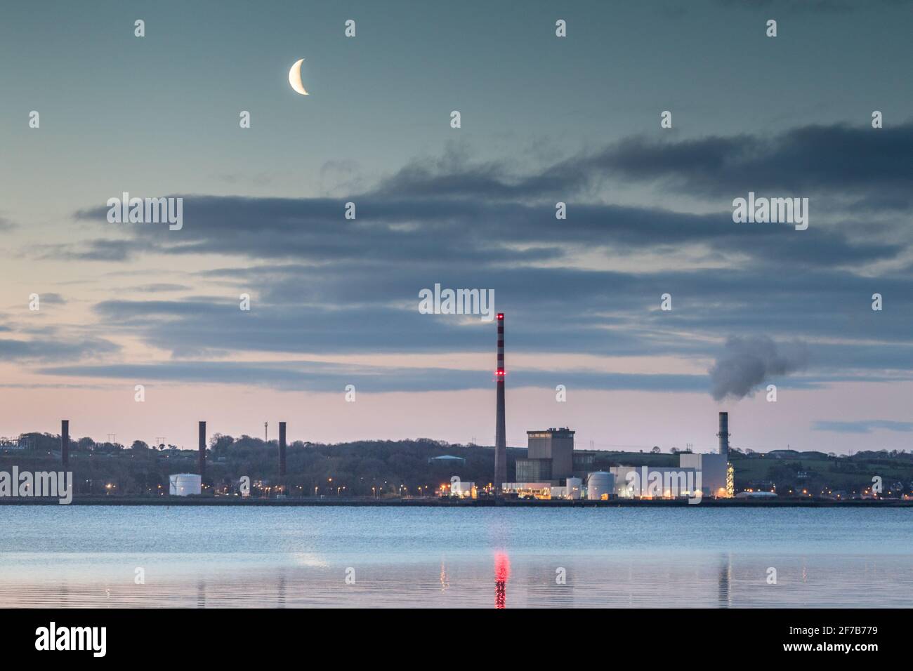 Aghada, Cork, Ireland. 06th April, 2021. A waning Moon begining to rise before dawn over the ESB generating station in Aghada, Co. Cork, Ireland. - Credit; David Creedon / Alamy Live News Stock Photo