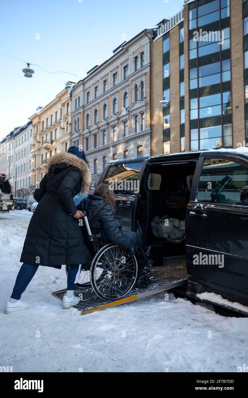 Carer helping woman on wheelchair to get into car Stock Photo Alamy