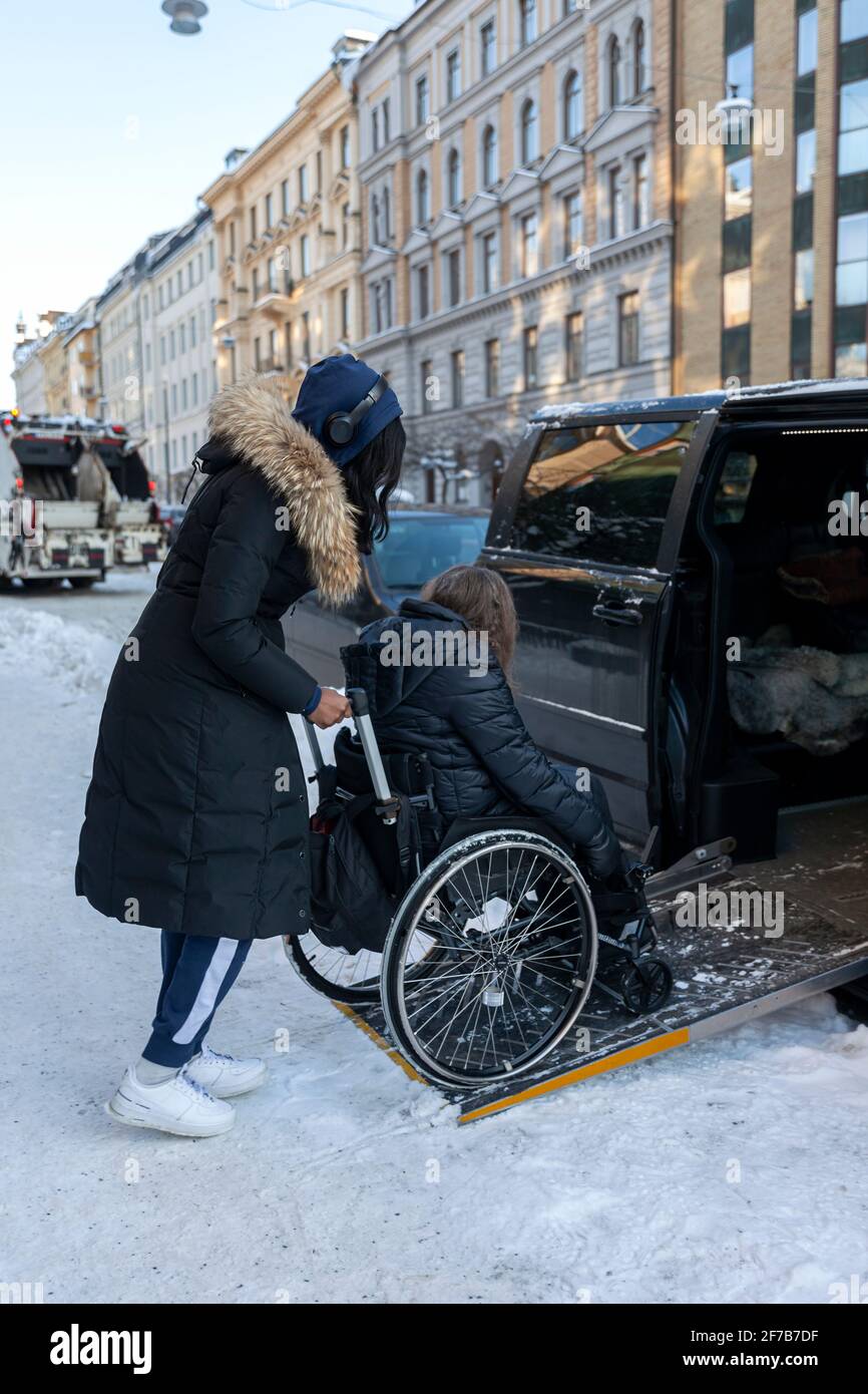Carer helping woman on wheelchair to get into car Stock Photo Alamy