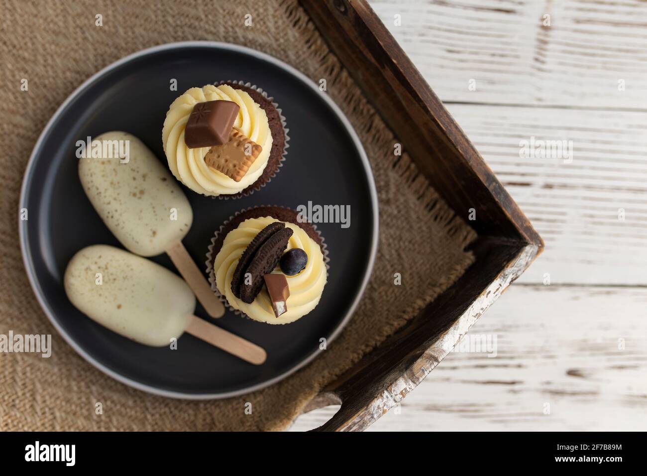 White cookie ice creams on a stick and tasty muffins and cupcakes on a